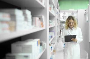 pharmacist-white-uniform-walking-by-shelf-with-medicines-checking-inventory